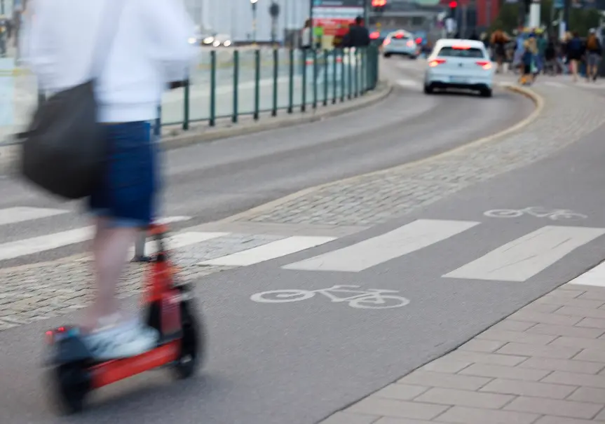 En person åker på en sparkcykel på en cykelbana i stadsmiljö